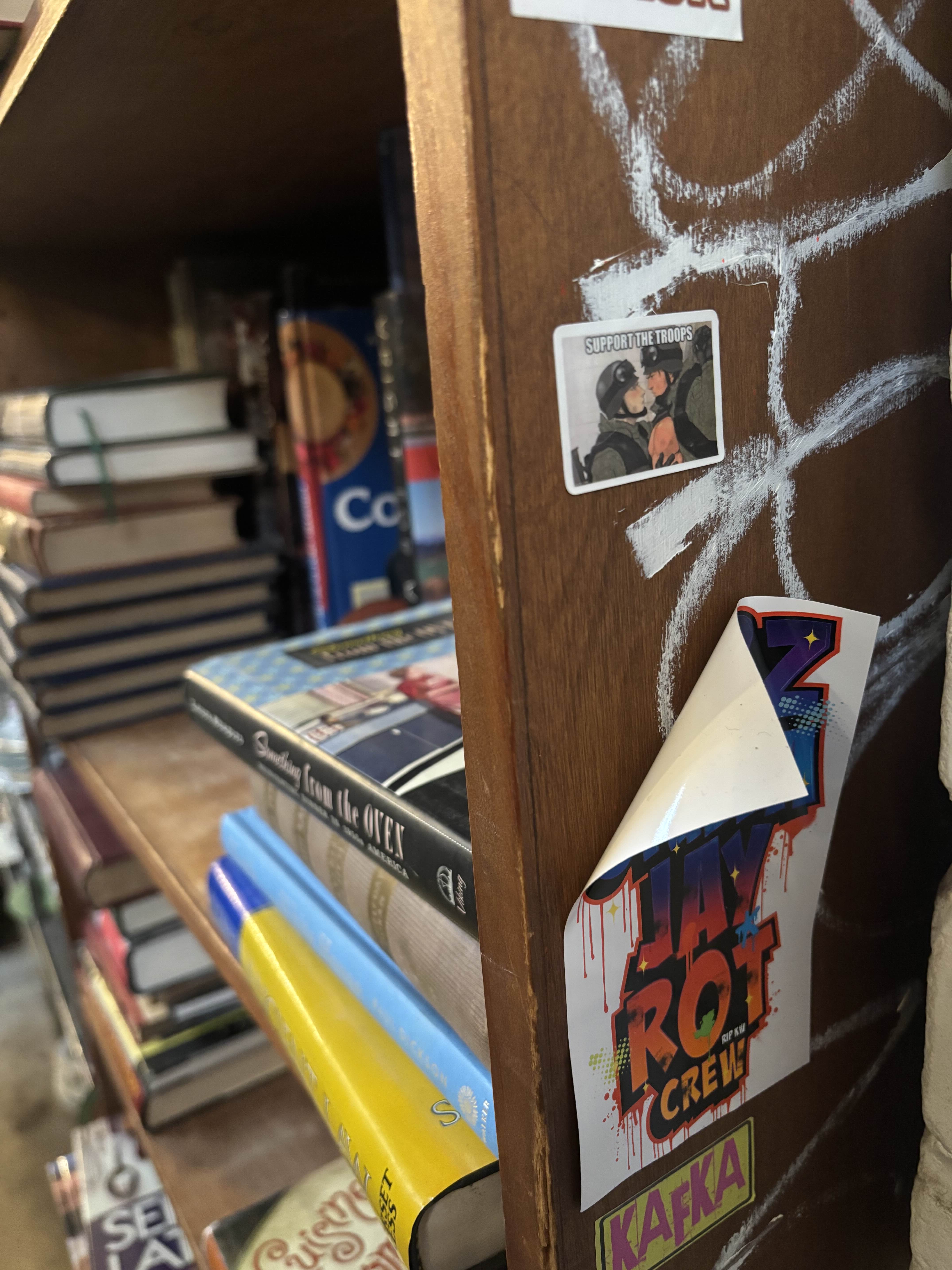 a sticker which says support the troops and features two soldiers staring at each other on a shelf.